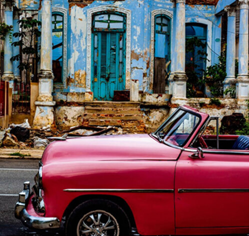 Old red car in front of old building in Havana Cuba